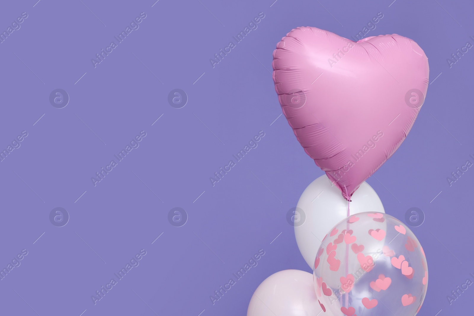 Photo of Bunch of heart and round shaped balloons on violet background, space for text. Birthday party