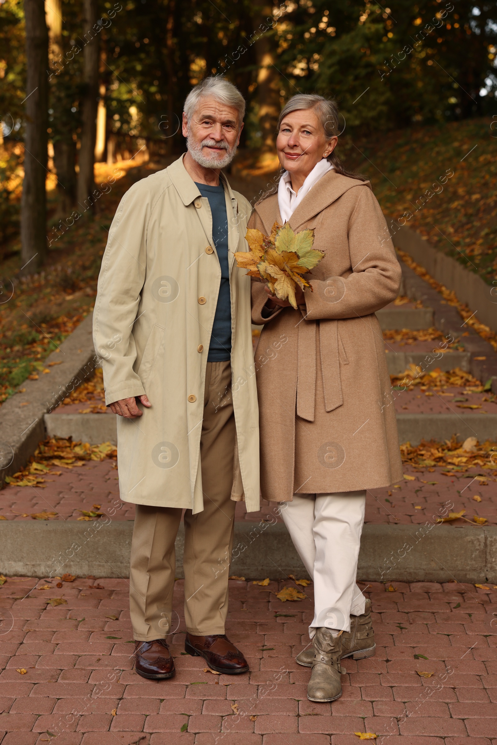 Photo of Affectionate senior couple with dry leaves in autumn park