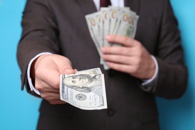 Photo of Man holding money on light blue background, closeup. Currency exchange