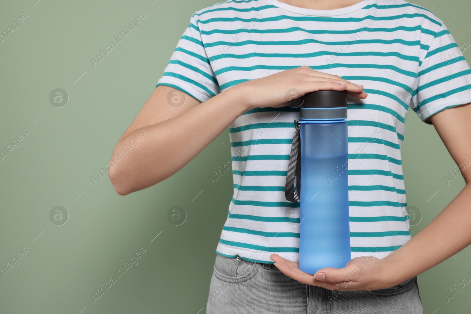 Photo of Woman holding bottle of water on green background, closeup. Space for text