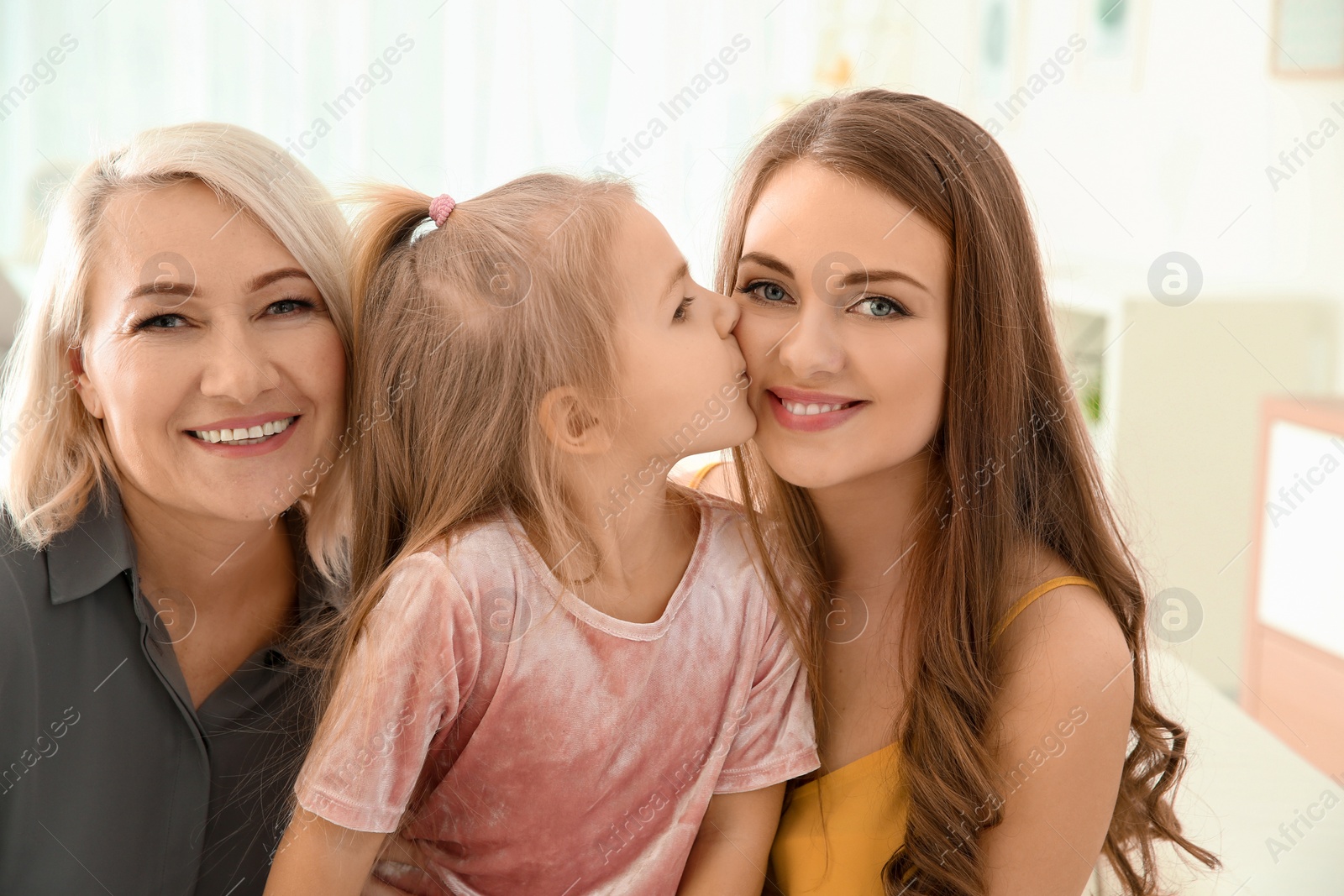 Photo of Happy young woman with her mother and daughter at home