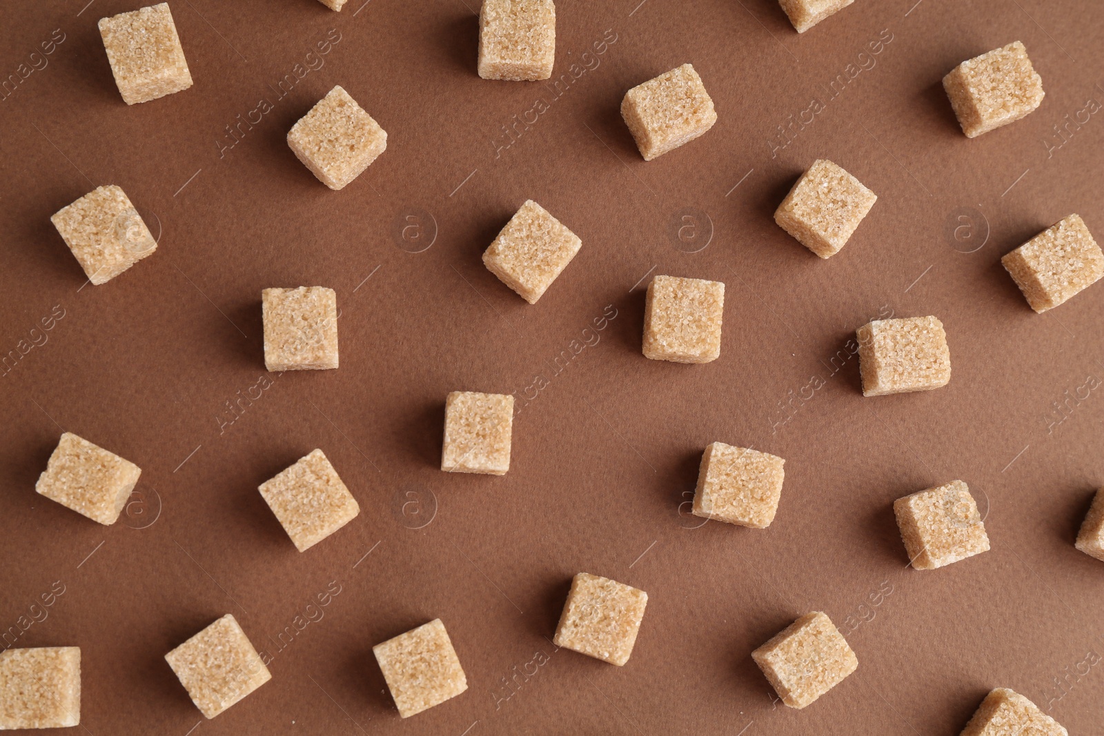 Photo of Brown sugar cubes on color background, top view