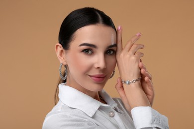 Young woman with elegant jewelry on beige background