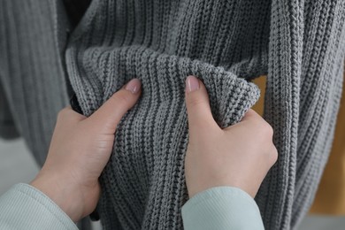 Woman touching clothes made of soft knitted fabric, closeup