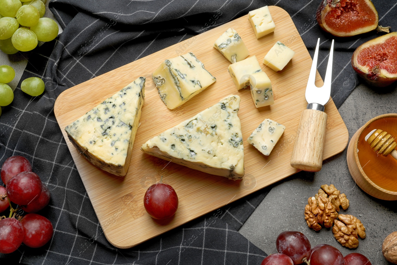 Photo of FLat lay composition with board of delicious blue cheese on table