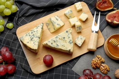 FLat lay composition with board of delicious blue cheese on table