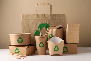 Set of eco friendly food packaging with recycling symbols on white table against beige background