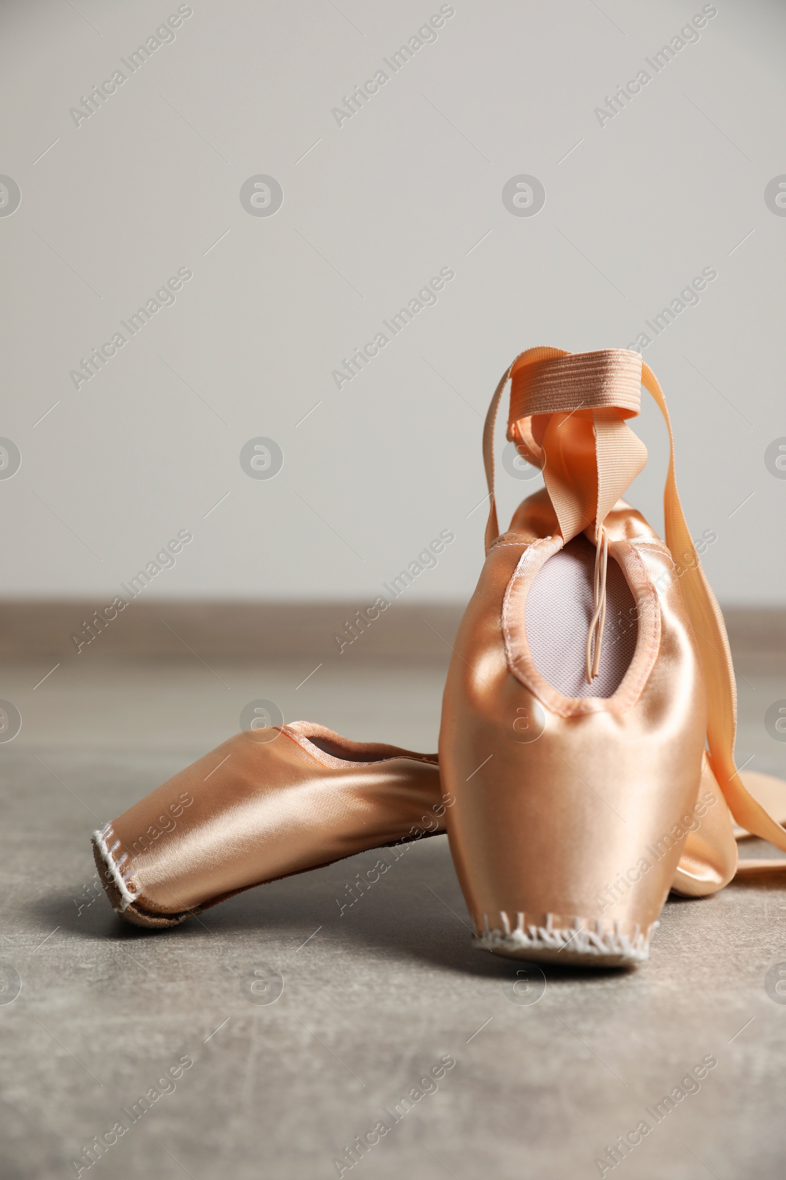 Photo of Ballet shoes. Elegant pointes on grey textured floor against white wall