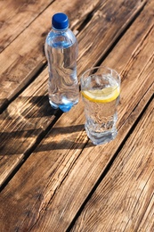 Photo of Glass and bottle of refreshing drink for hot summer day on wooden table, space for text