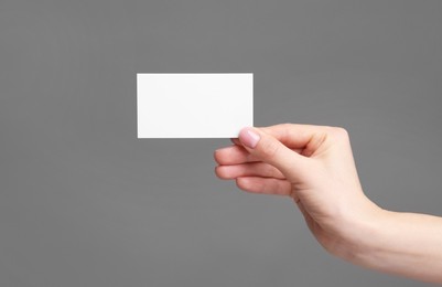 Photo of Woman holding blank business card on grey background, closeup. Space for text