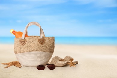 Image of Bag with sunscreen and accessories on sunny ocean beach, space for text. Summer vacation