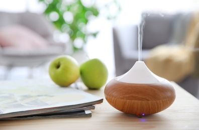 Photo of Aroma oil diffuser on table against blurred background