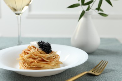 Tasty spaghetti with tomato sauce and black caviar served on table, closeup. Exquisite presentation of pasta dish