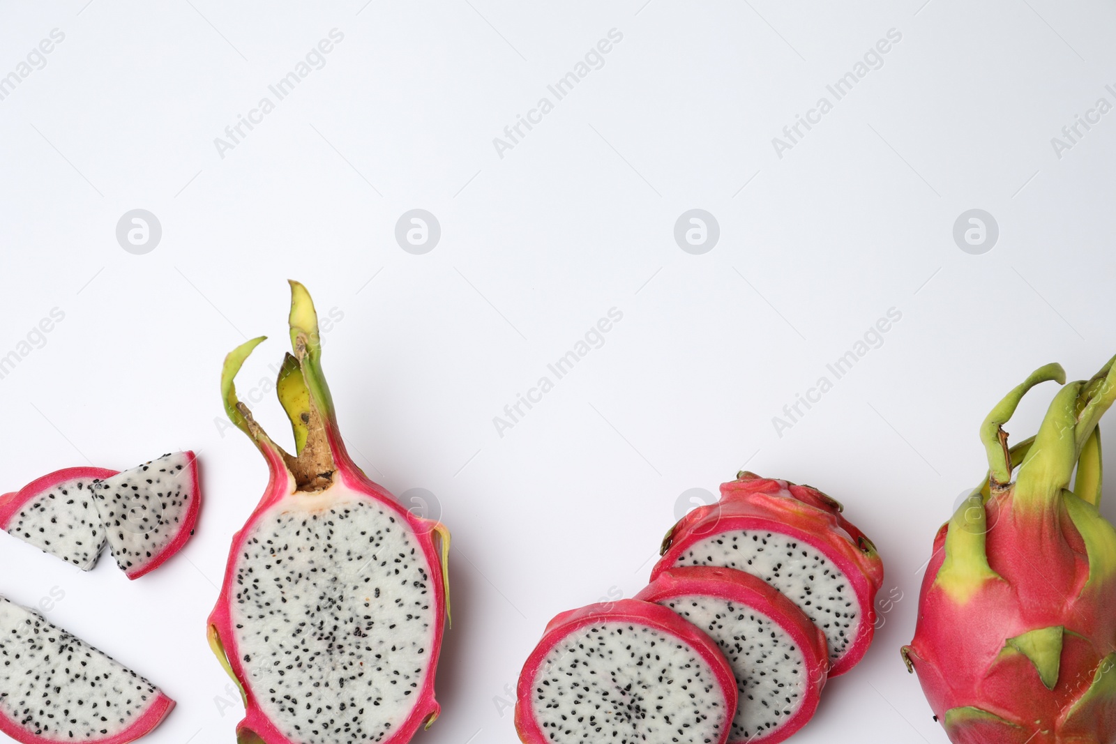 Photo of Delicious cut and whole dragon fruits (pitahaya) on white background, top view