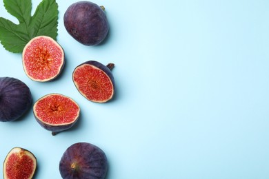 Photo of Fresh ripe figs with green leaf on light blue background, flat lay. Space for text