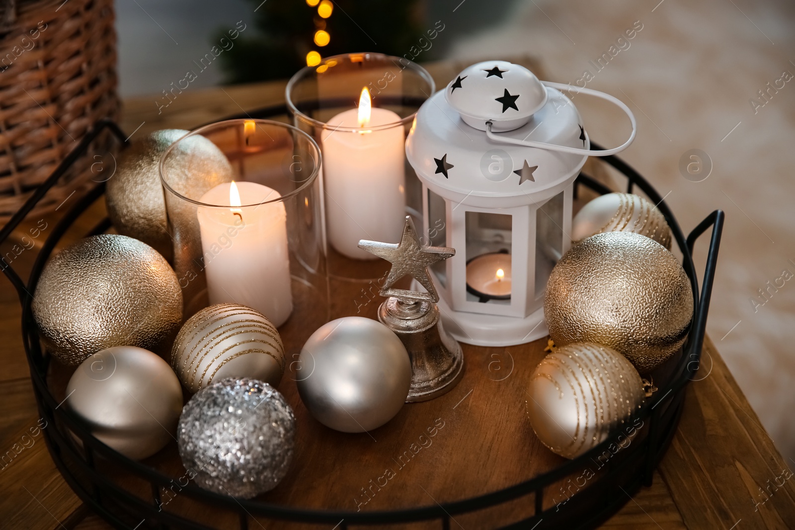 Photo of Burning candles, lantern and Christmas balls on wooden table indoors, closeup