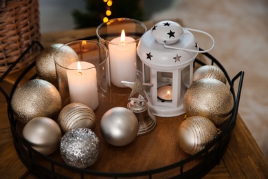 Burning candles, lantern and Christmas balls on wooden table indoors, closeup