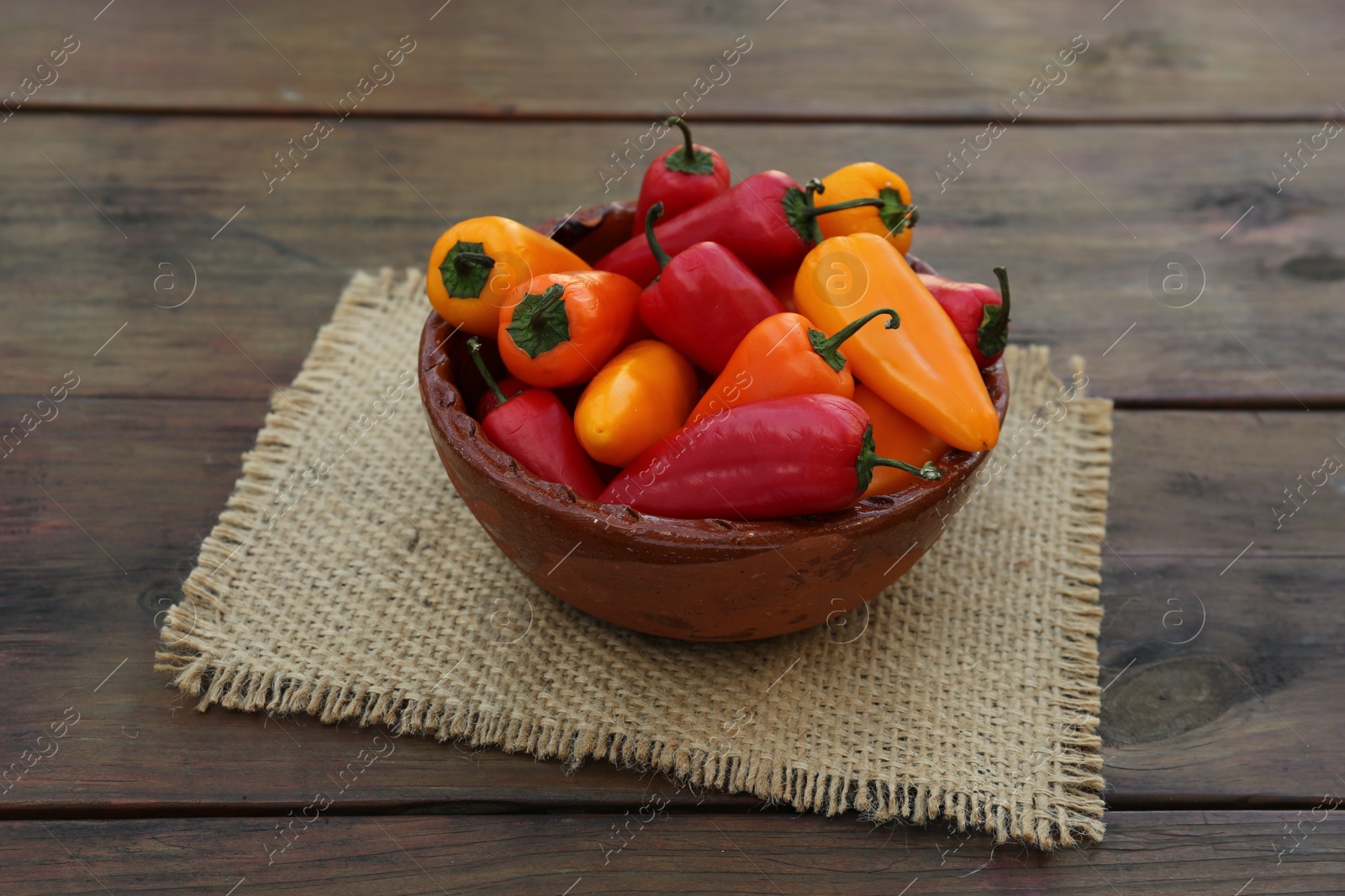 Photo of Bowl with ripe bell peppers on wooden table