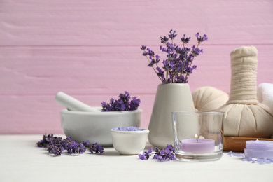Cosmetic products and lavender flowers on white wooden table