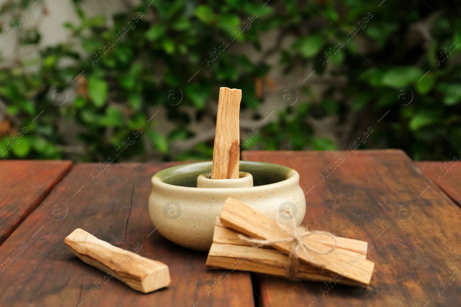 Photo of Palo Santo (holy wood) sticks and holder on wooden table outdoors