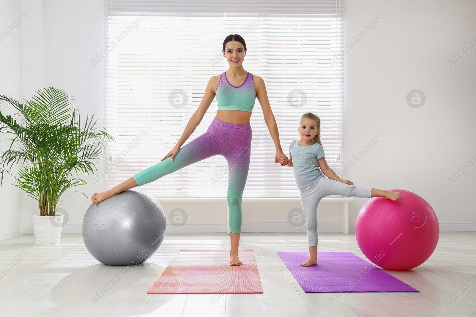 Photo of Woman and daughter doing exercise with fitness balls at home