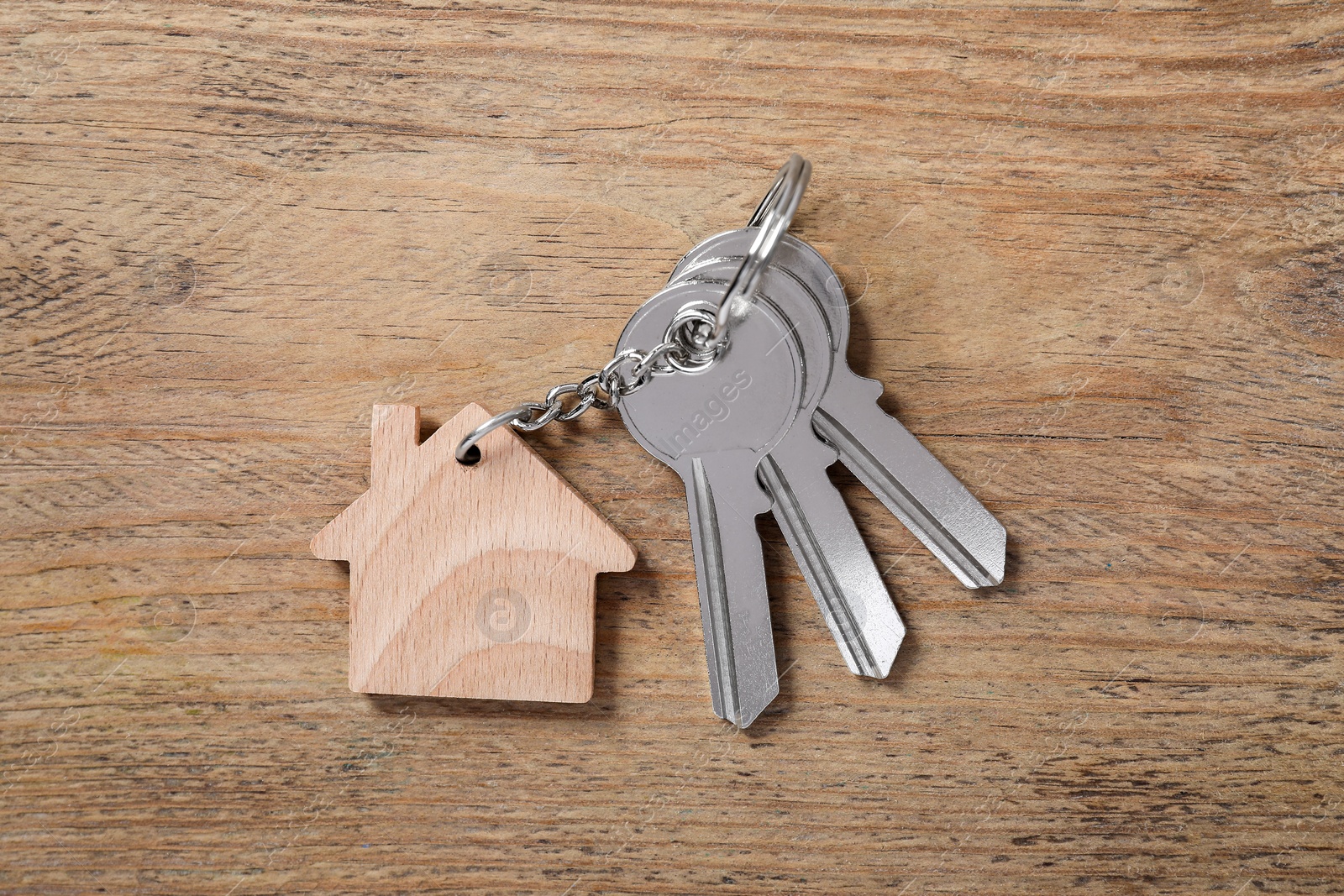 Photo of Keys with keychain in shape of house on wooden table, top view