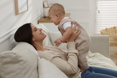 Photo of Happy young mother with her baby on sofa in living room