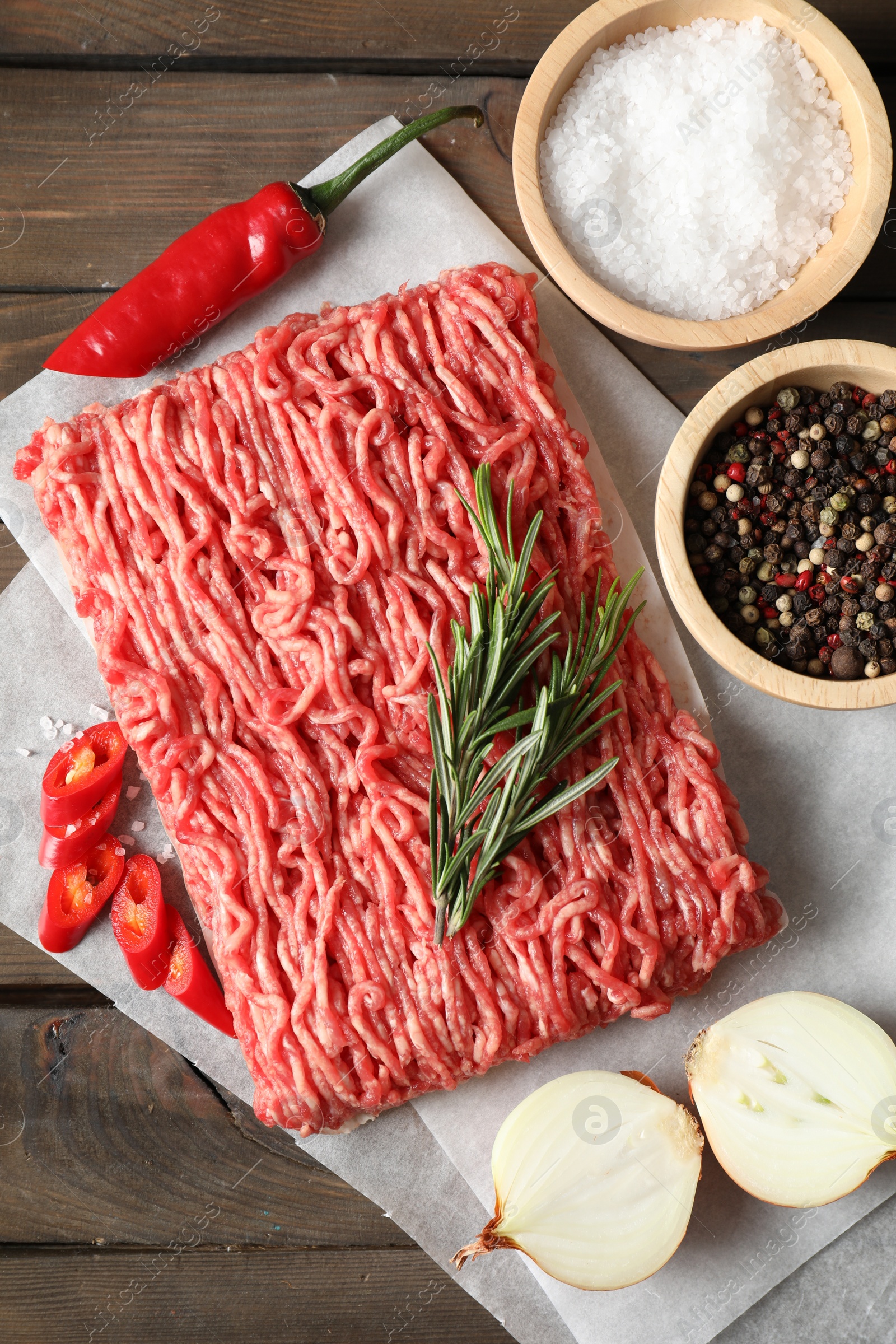 Photo of Raw ground meat, spices, rosemary and onion on wooden table, flat lay