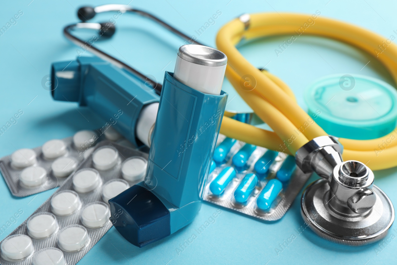 Photo of Asthma inhalers, stethoscope and pills on color background, closeup
