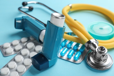 Photo of Asthma inhalers, stethoscope and pills on color background, closeup