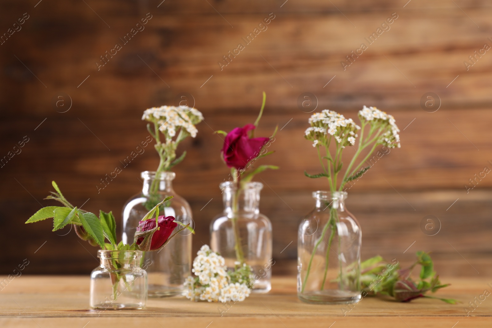 Photo of Different flowers in glass bottles on wooden table