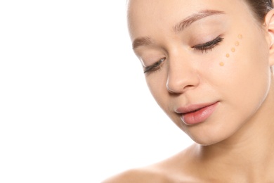 Portrait of young woman with liquid foundation on her face against white background