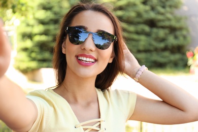 Young woman taking selfie outdoors on sunny day