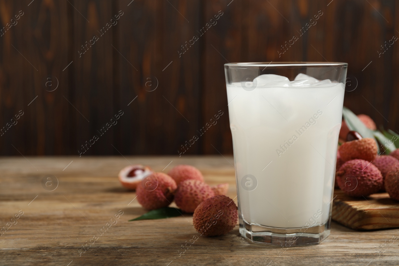 Photo of Lychee juice and fresh fruits on wooden table. Space for text