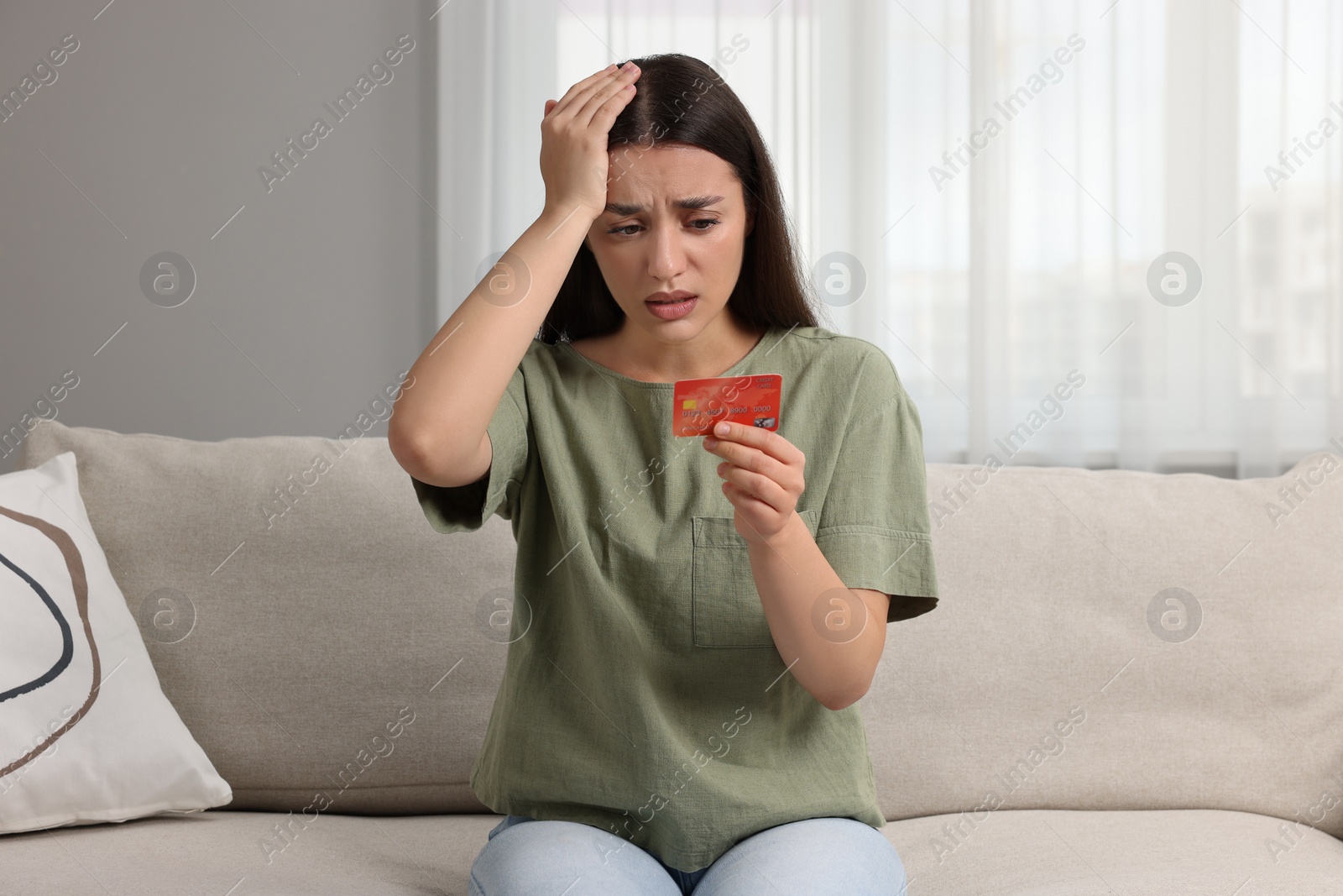 Photo of Stressed woman with credit card at home. Be careful - fraud