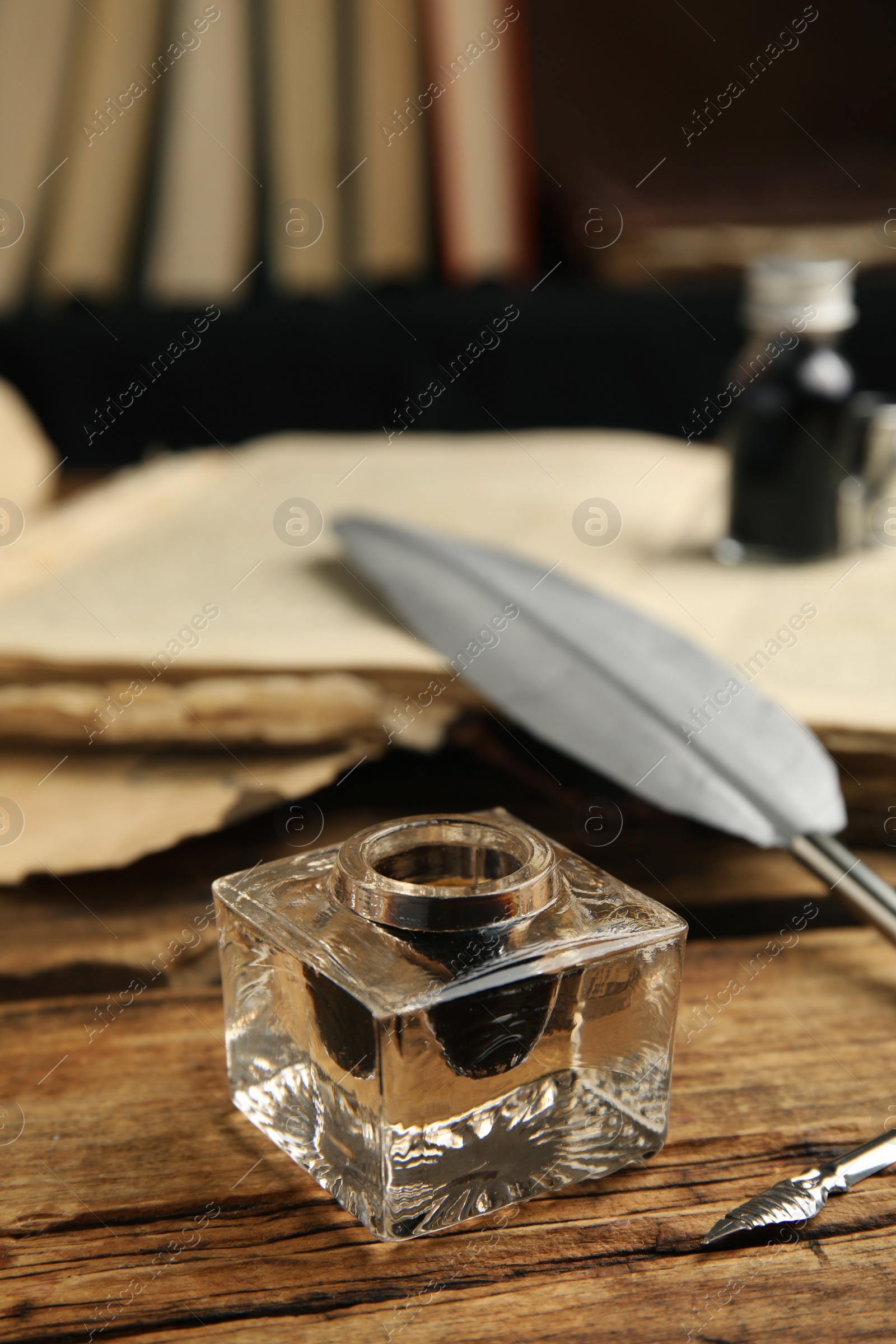 Photo of Feather pen and inkwell on wooden table