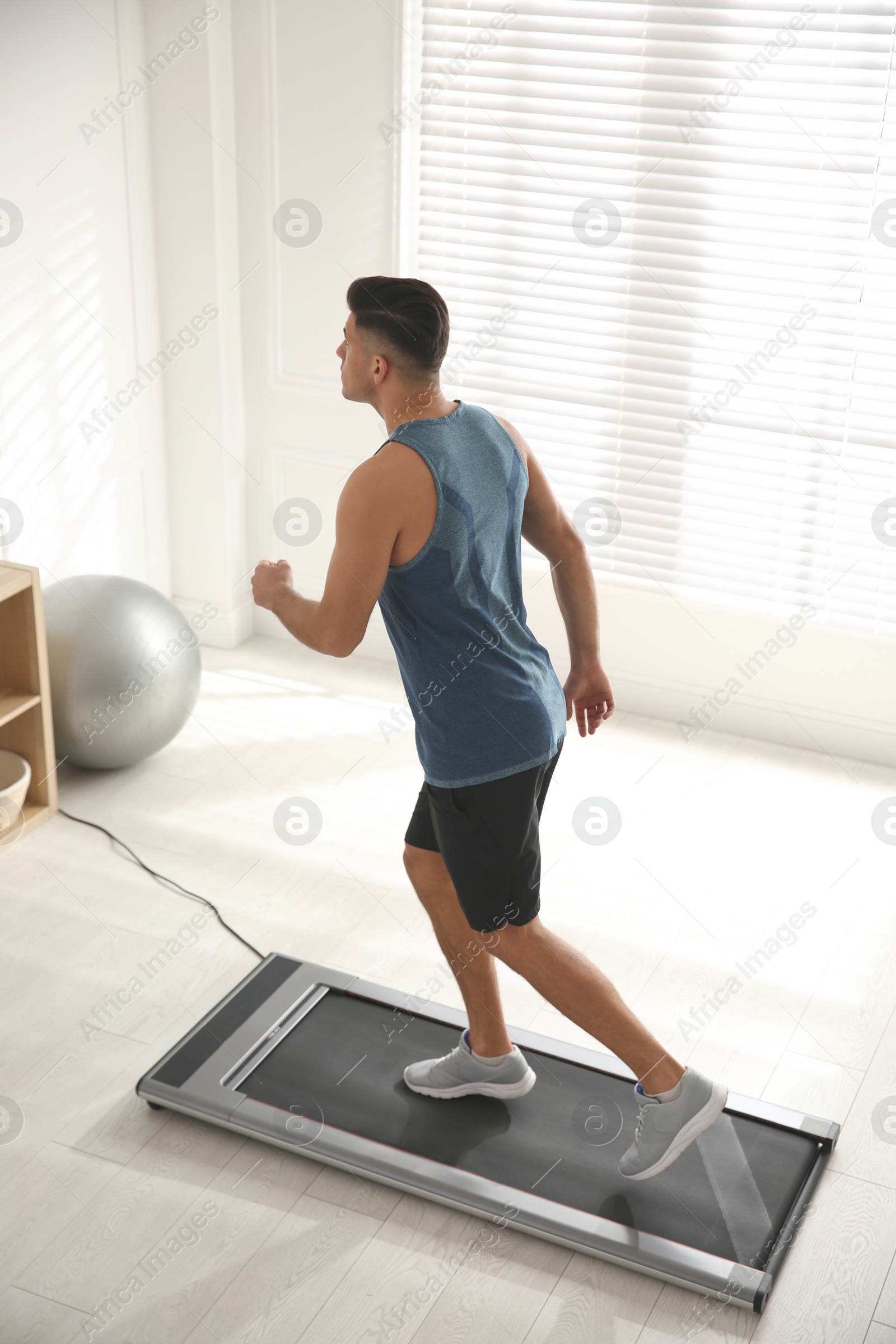 Photo of Sporty man training on walking treadmill at home