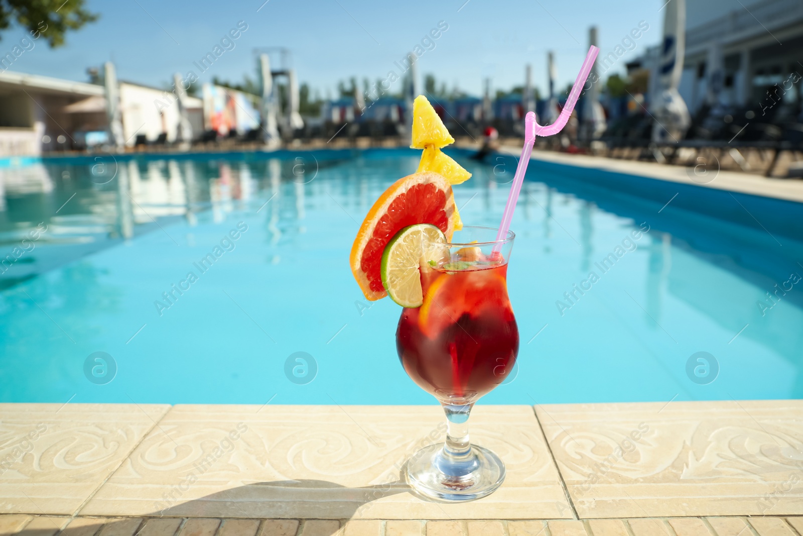 Photo of Tasty refreshing cocktail on edge of swimming pool. Party drink