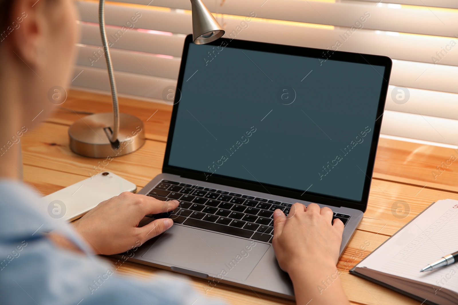 Photo of Woman working with modern laptop at wooden table, closeup. Space for design