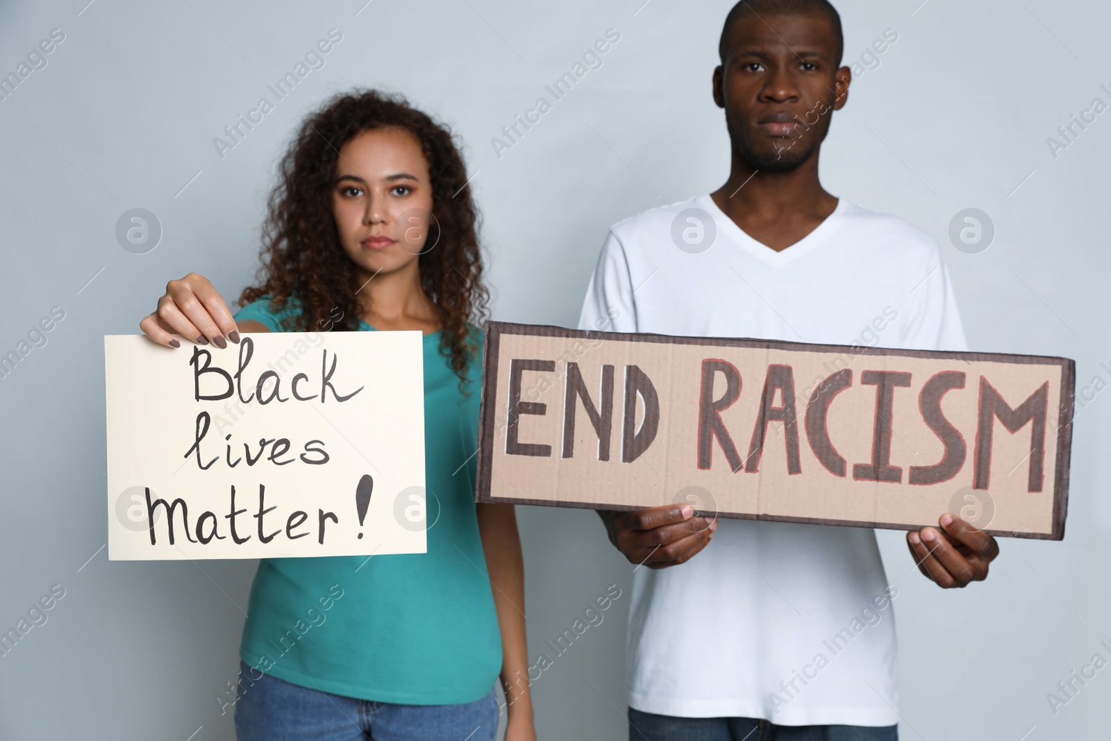 Photo of African American woman and man holding signs on grey background. Racism concept