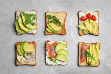 Photo of Delicious avocado sandwiches on marble table, flat lay