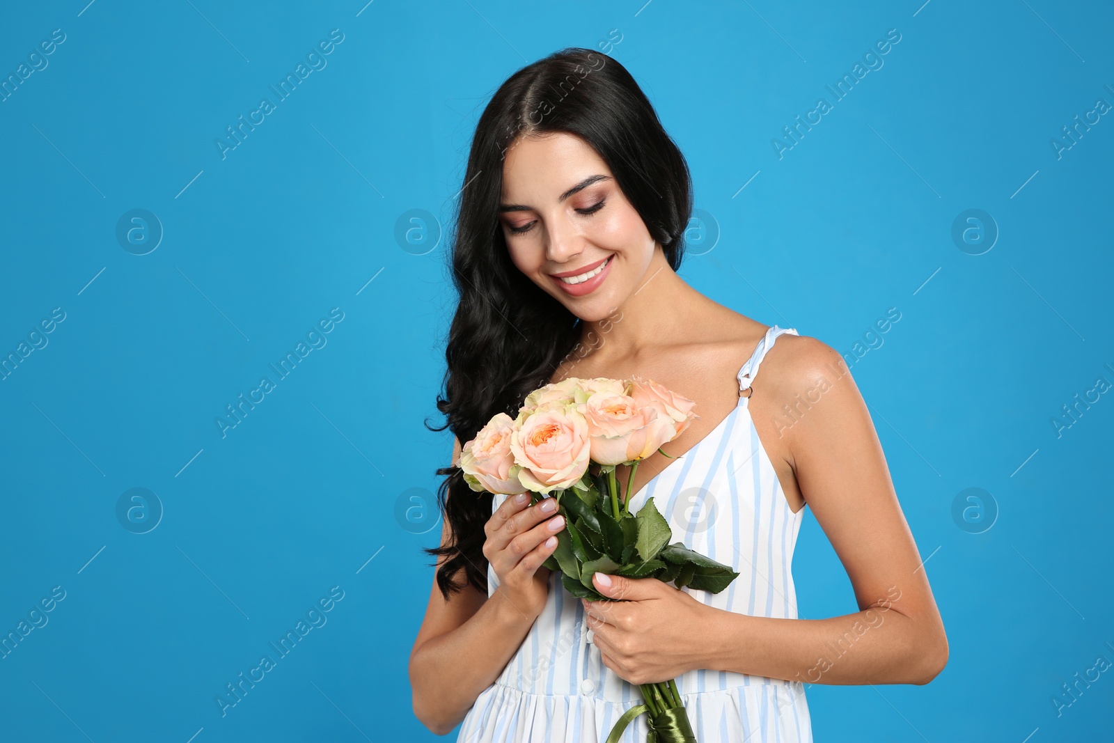 Photo of Portrait of smiling woman with beautiful bouquet on light blue background