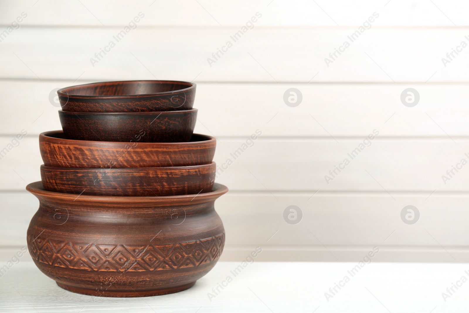 Photo of Set of clay utensils on white wooden table. Space for text