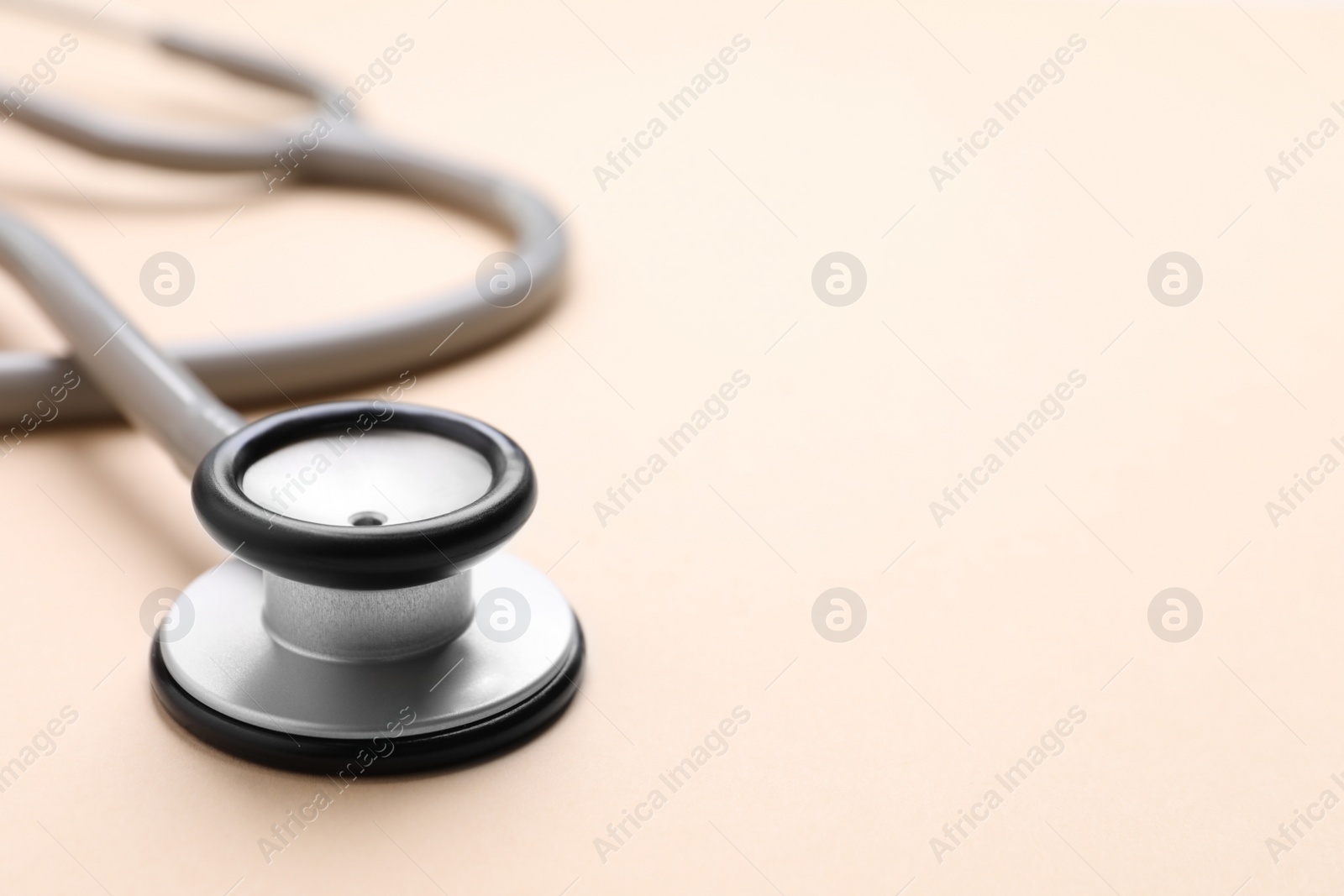 Photo of Stethoscope on beige background, closeup. Space for text