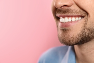 Smiling man with perfect teeth on color background, closeup. Space for text