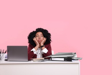 Photo of Stressful deadline. Exhausted woman sitting at white desk against pink background. Space for text