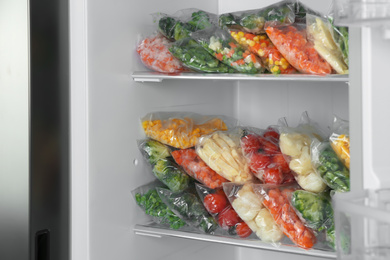 Plastic bags with different frozen vegetables in refrigerator