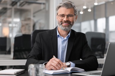 Photo of Portrait of smiling man at table in office. Lawyer, businessman, accountant or manager