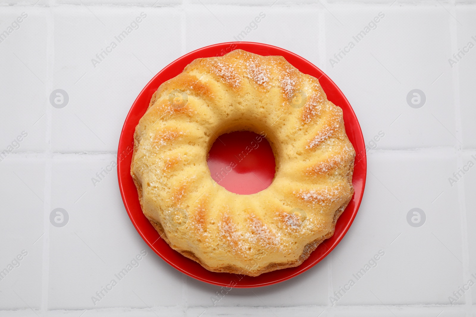 Photo of Delicious freshly baked sponge cake on white tiled table, top view