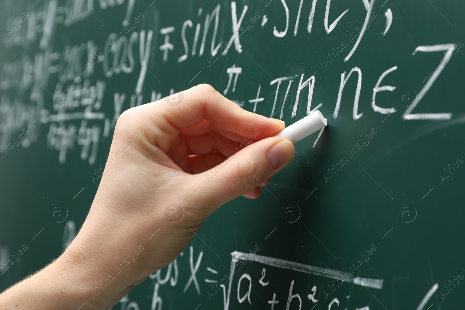 Photo of Teacher writing down math equation on green board, closeup